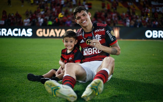 Ayrton Lucas ao lado do filho, com medalha da Libertadores conquistada pelo Flamengo.