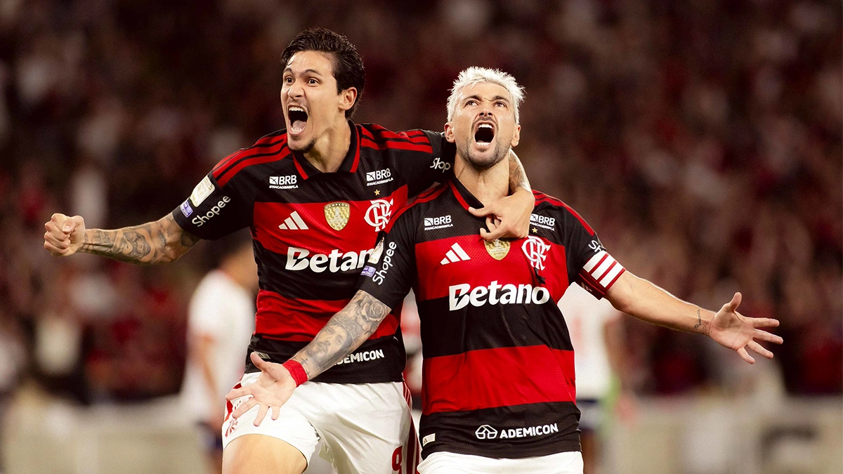 Clube rubro-negro unido durante uma partida de futebol. Jogadores se abraçam.